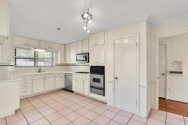 kitchen with decorative backsplash, appliances with stainless steel finishes, crown molding, sink, and light tile patterned floors