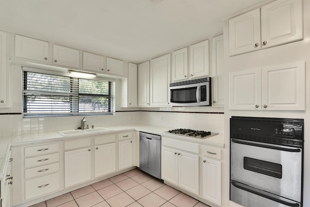 kitchen with sink, white cabinets, stainless steel appliances, and light tile patterned floors