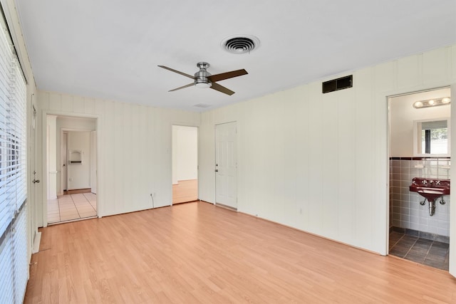 interior space featuring light wood-type flooring, tile walls, and ceiling fan