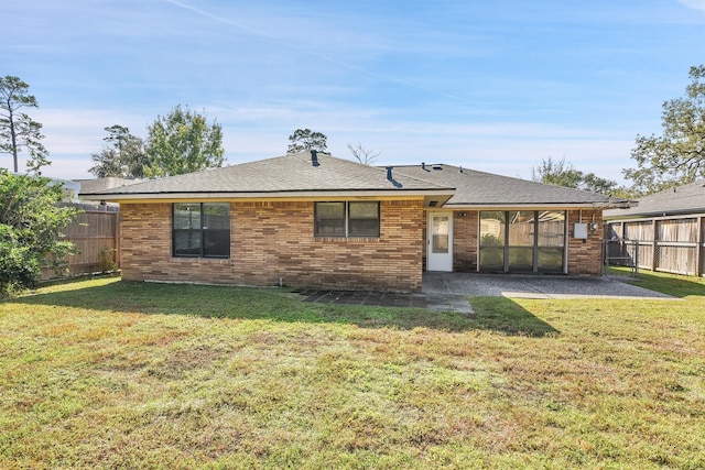 rear view of property featuring a lawn, a patio area, and a sunroom