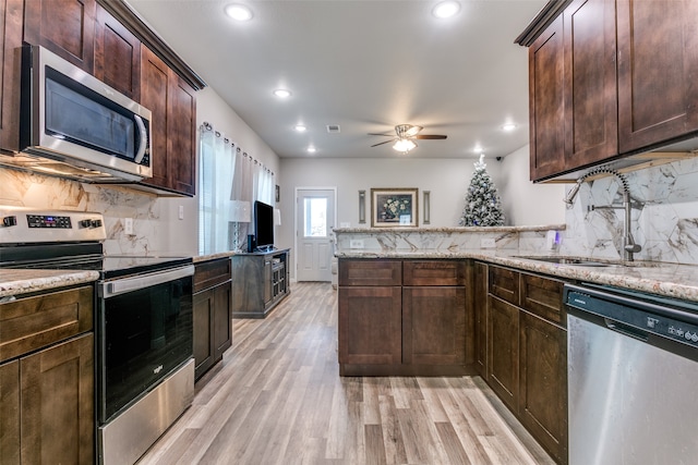 kitchen with light stone counters, stainless steel appliances, and light hardwood / wood-style flooring