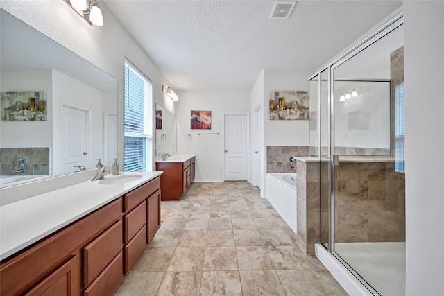 bathroom with separate shower and tub, vanity, and a textured ceiling