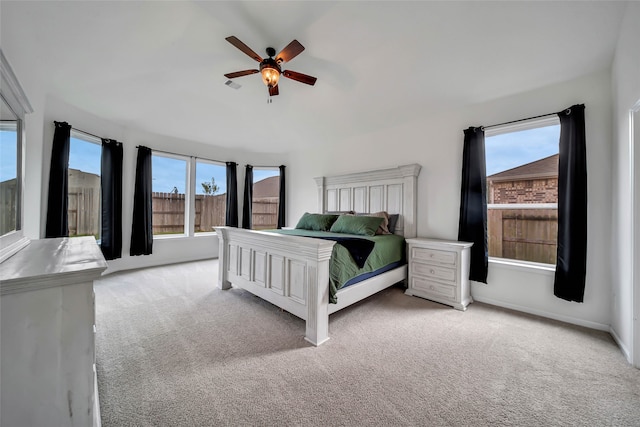 bedroom featuring ceiling fan, light carpet, and multiple windows