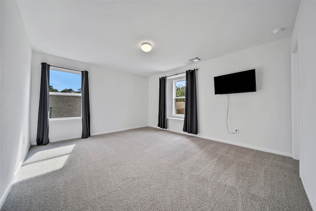 unfurnished room featuring light carpet and plenty of natural light