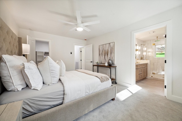 carpeted bedroom featuring a walk in closet, a closet, ensuite bathroom, and ceiling fan