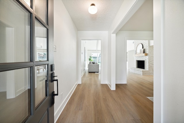 corridor with light wood-type flooring and a textured ceiling