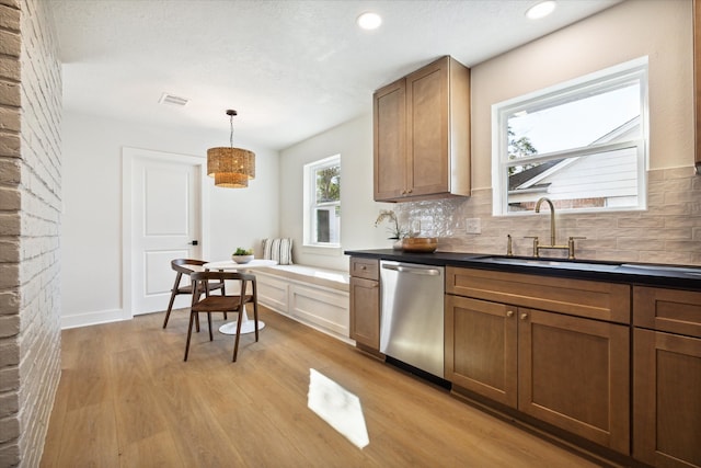 kitchen featuring backsplash, sink, hanging light fixtures, light hardwood / wood-style flooring, and stainless steel dishwasher