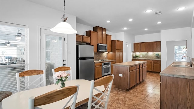 kitchen featuring sink, a healthy amount of sunlight, stainless steel appliances, backsplash, and pendant lighting