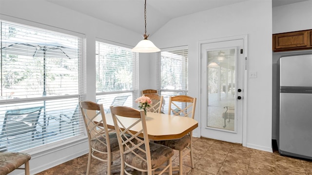 tiled dining space featuring vaulted ceiling