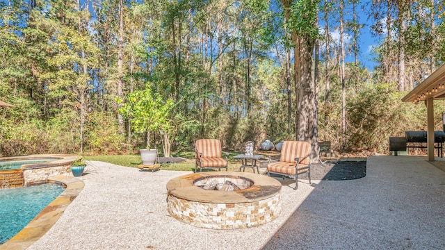 view of patio / terrace with a swimming pool with hot tub and an outdoor fire pit