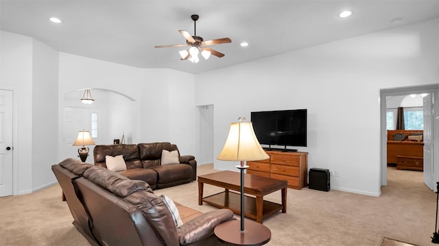 carpeted living room with ceiling fan and a towering ceiling