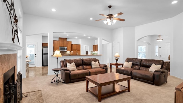 carpeted living room with ceiling fan and a tiled fireplace