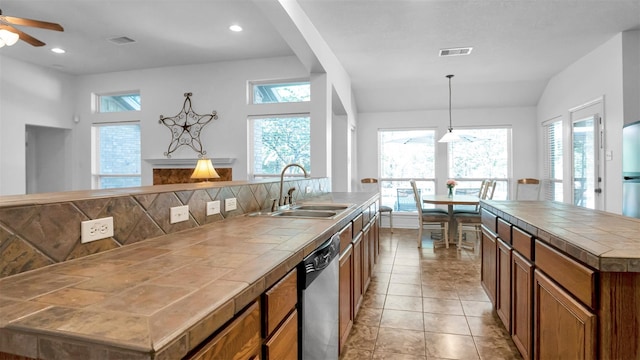 kitchen with pendant lighting, a center island, stainless steel dishwasher, light tile patterned floors, and tile counters