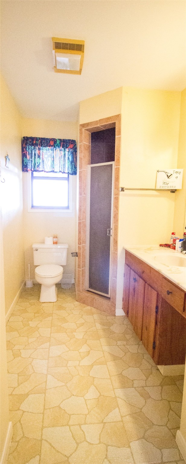 bathroom featuring vanity, an enclosed shower, and toilet