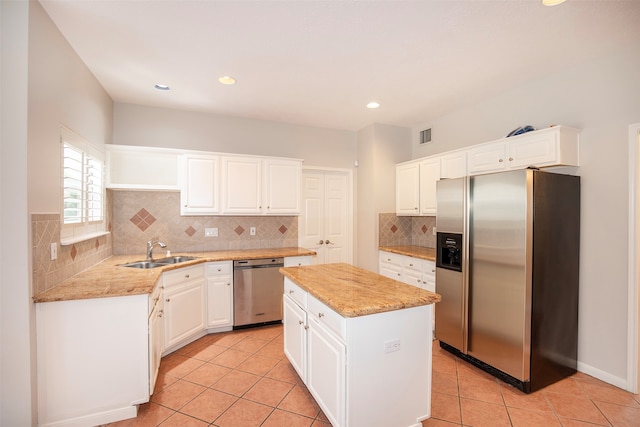 kitchen with a center island, sink, stainless steel appliances, light tile patterned floors, and white cabinets