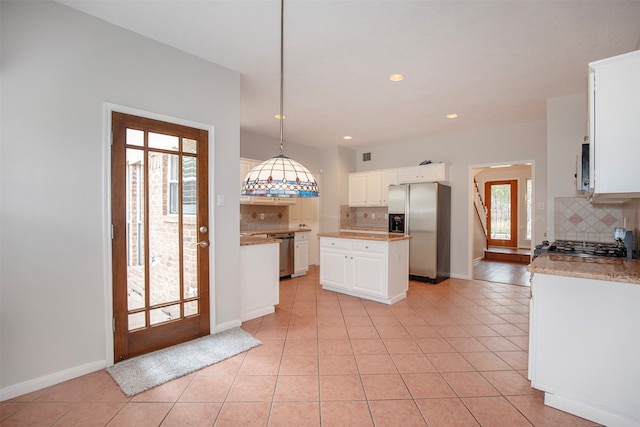 kitchen featuring white cabinets, appliances with stainless steel finishes, a kitchen island, and plenty of natural light