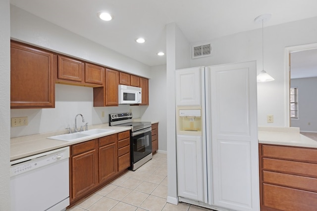 kitchen featuring decorative light fixtures, white appliances, sink, and light tile patterned floors