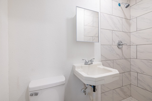 bathroom featuring toilet and a tile shower