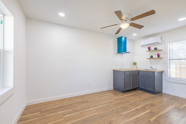 bar featuring an AC wall unit, ceiling fan, light hardwood / wood-style flooring, and sink