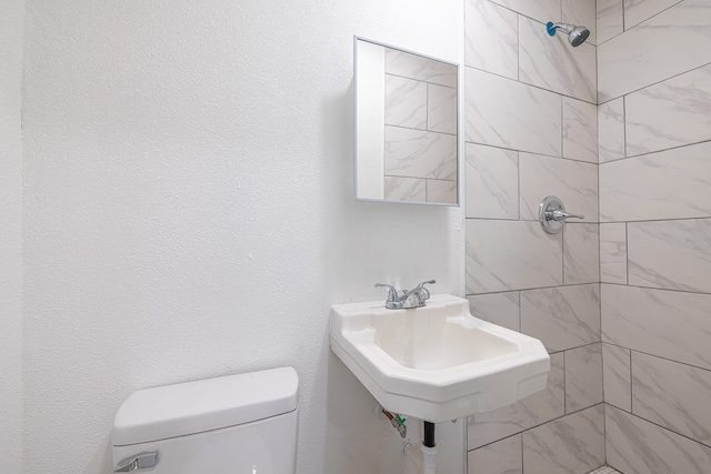 bathroom with sink, toilet, and tiled shower