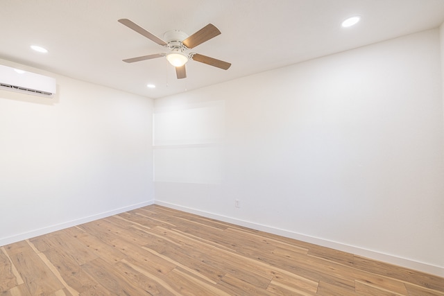 spare room with hardwood / wood-style floors, ceiling fan, and a wall unit AC