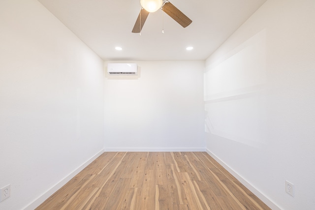 empty room featuring hardwood / wood-style flooring, an AC wall unit, and ceiling fan