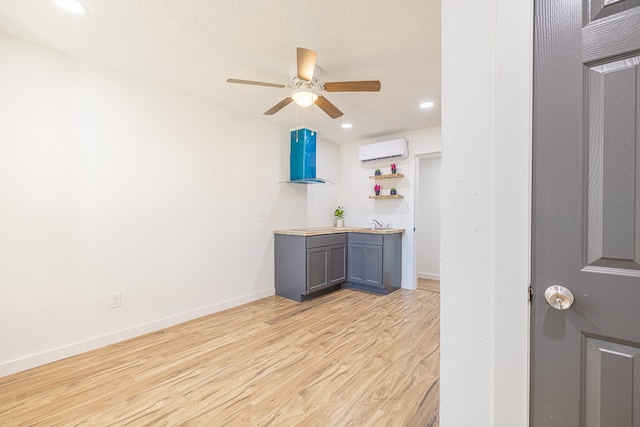 bar featuring ceiling fan, light wood-type flooring, and a wall unit AC