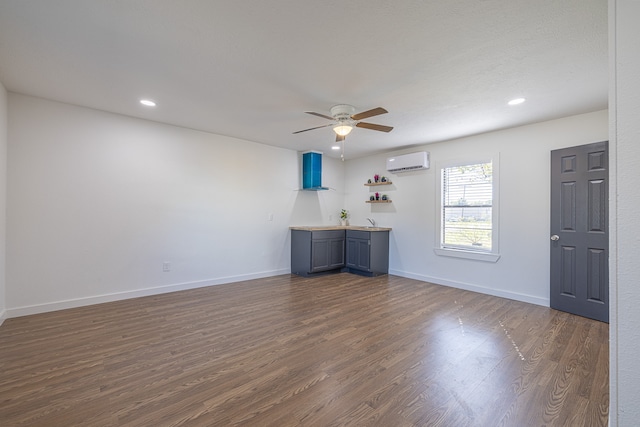 unfurnished room featuring ceiling fan, dark wood-type flooring, and a wall unit AC