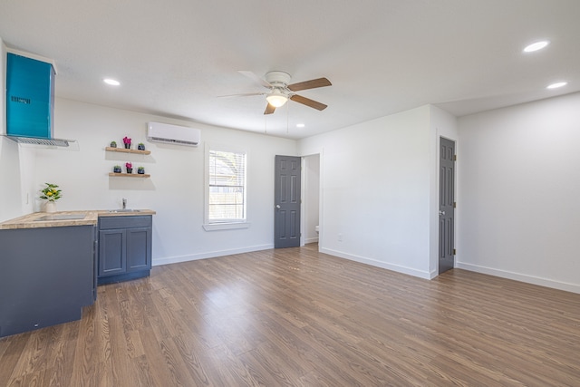 interior space with blue cabinetry, ceiling fan, sink, dark hardwood / wood-style floors, and a wall mounted AC