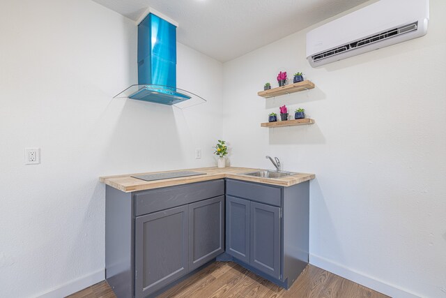 bar with wood counters, wall chimney exhaust hood, a wall mounted AC, dark wood-type flooring, and sink