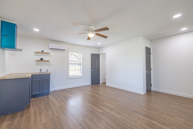 unfurnished living room with ceiling fan, sink, an AC wall unit, and dark wood-type flooring