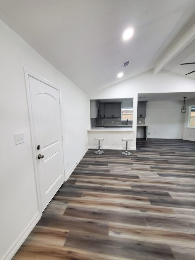 living room featuring vaulted ceiling with beams and dark wood-type flooring