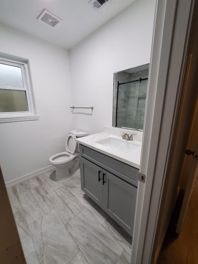 bathroom featuring vanity, a shower with shower door, and toilet