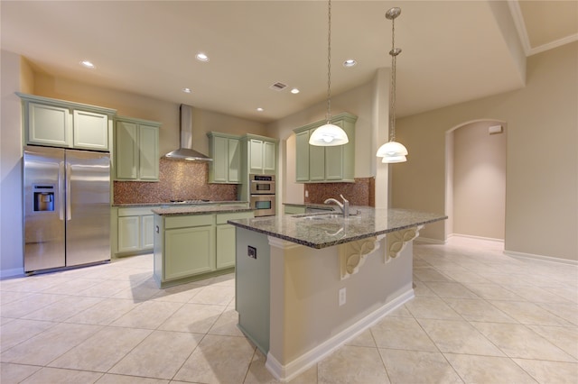 kitchen featuring pendant lighting, sink, wall chimney exhaust hood, tasteful backsplash, and stainless steel appliances