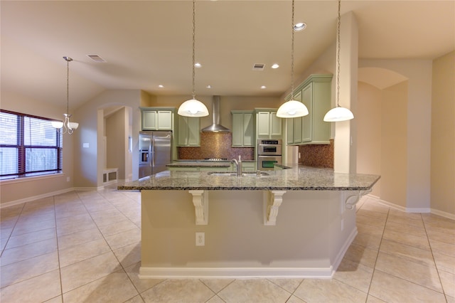 kitchen with a breakfast bar, wall chimney exhaust hood, pendant lighting, and appliances with stainless steel finishes