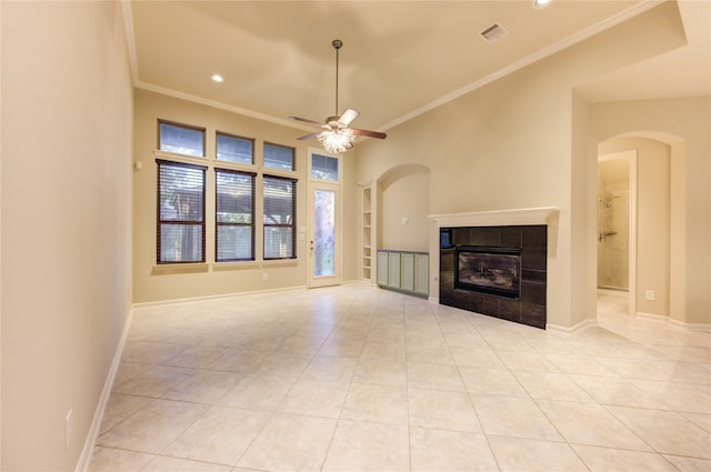 unfurnished living room with a tiled fireplace, ceiling fan, light tile patterned flooring, and ornamental molding