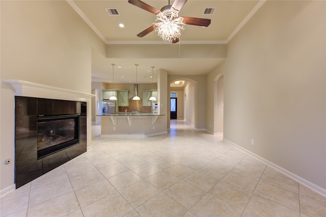 unfurnished living room with a fireplace, light tile patterned floors, ceiling fan, and crown molding