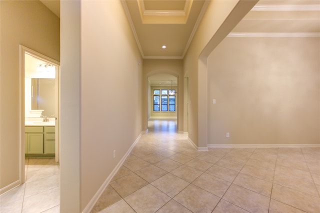 hallway with sink, light tile patterned floors, and ornamental molding