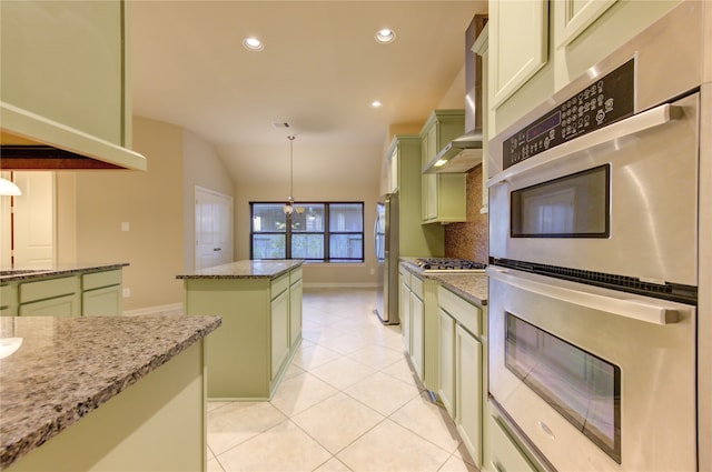 kitchen featuring lofted ceiling, light stone countertops, appliances with stainless steel finishes, decorative light fixtures, and a kitchen island