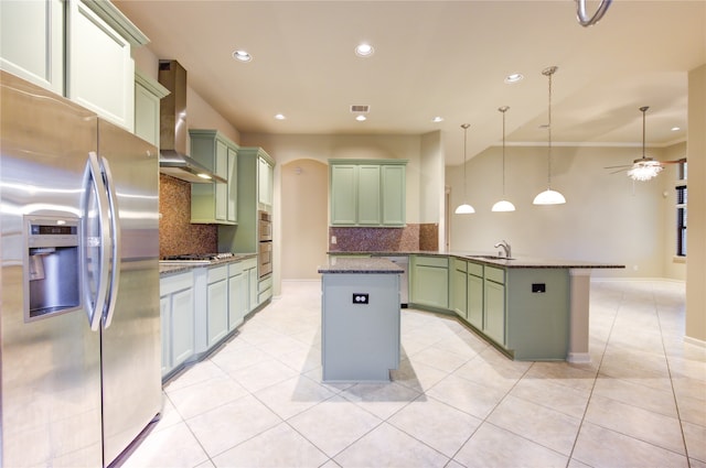 kitchen featuring backsplash, stainless steel appliances, sink, wall chimney range hood, and hanging light fixtures