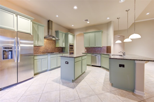 kitchen with appliances with stainless steel finishes, tasteful backsplash, wall chimney exhaust hood, decorative light fixtures, and a center island