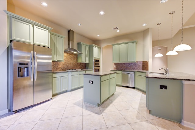 kitchen featuring wall chimney range hood, sink, hanging light fixtures, kitchen peninsula, and stainless steel appliances