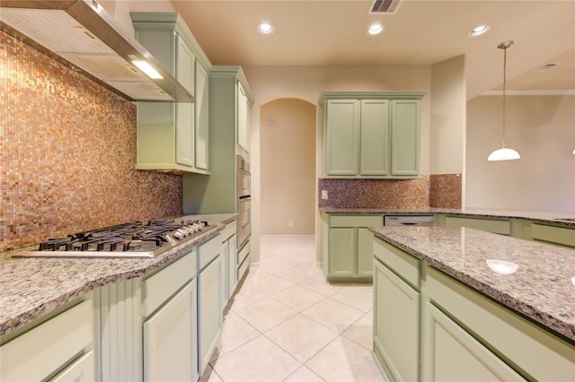 kitchen featuring backsplash, light stone counters, stainless steel gas cooktop, green cabinetry, and hanging light fixtures