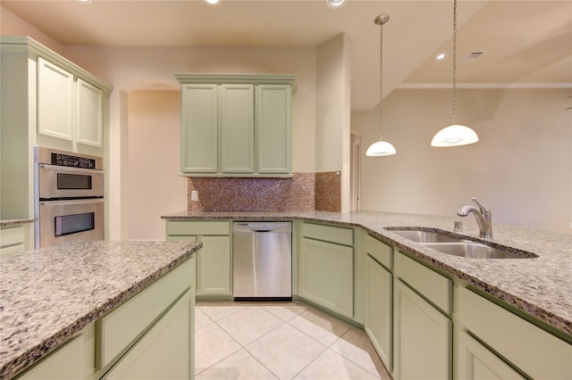 kitchen with sink, green cabinetry, appliances with stainless steel finishes, tasteful backsplash, and decorative light fixtures