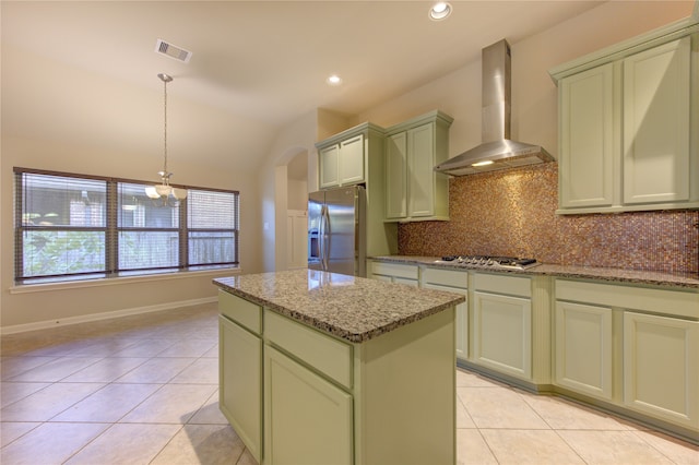 kitchen with light stone countertops, appliances with stainless steel finishes, pendant lighting, and wall chimney exhaust hood