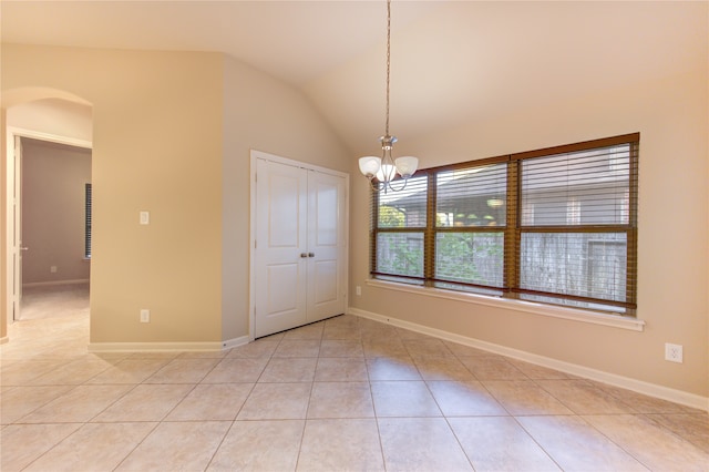 tiled empty room featuring a chandelier and lofted ceiling