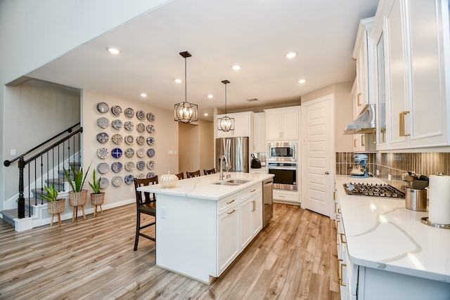 kitchen featuring white cabinetry, a center island with sink, stainless steel appliances, and sink