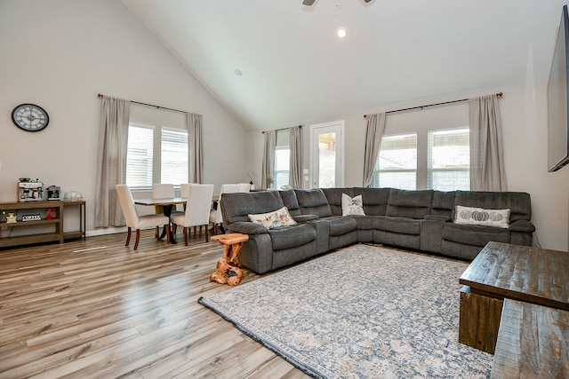 living room with ceiling fan, plenty of natural light, high vaulted ceiling, and light wood-type flooring