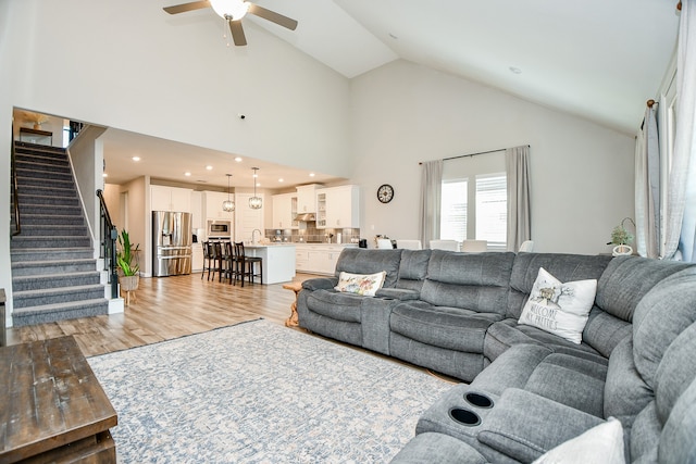 living room featuring high vaulted ceiling, light hardwood / wood-style flooring, and ceiling fan