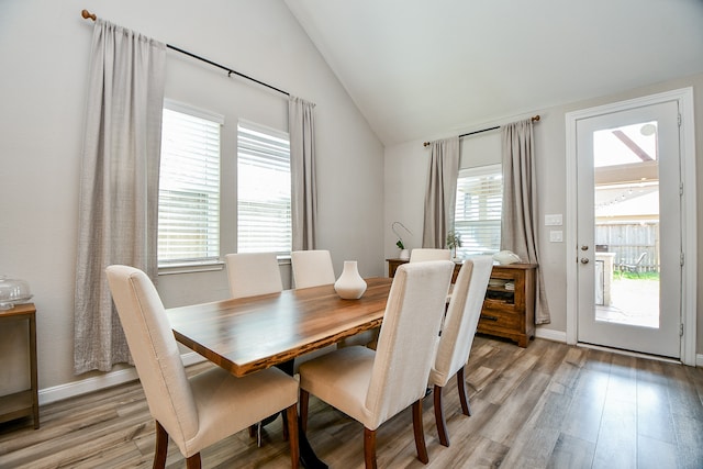 dining room featuring plenty of natural light, light wood-type flooring, and lofted ceiling